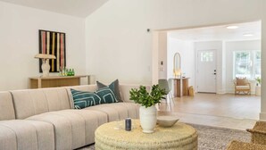 A modern living room with a beige sofa, a round coffee table, and a potted plant.