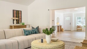 A living room with a sofa, a coffee table with a plant, a lamp, and a painting on the wall.