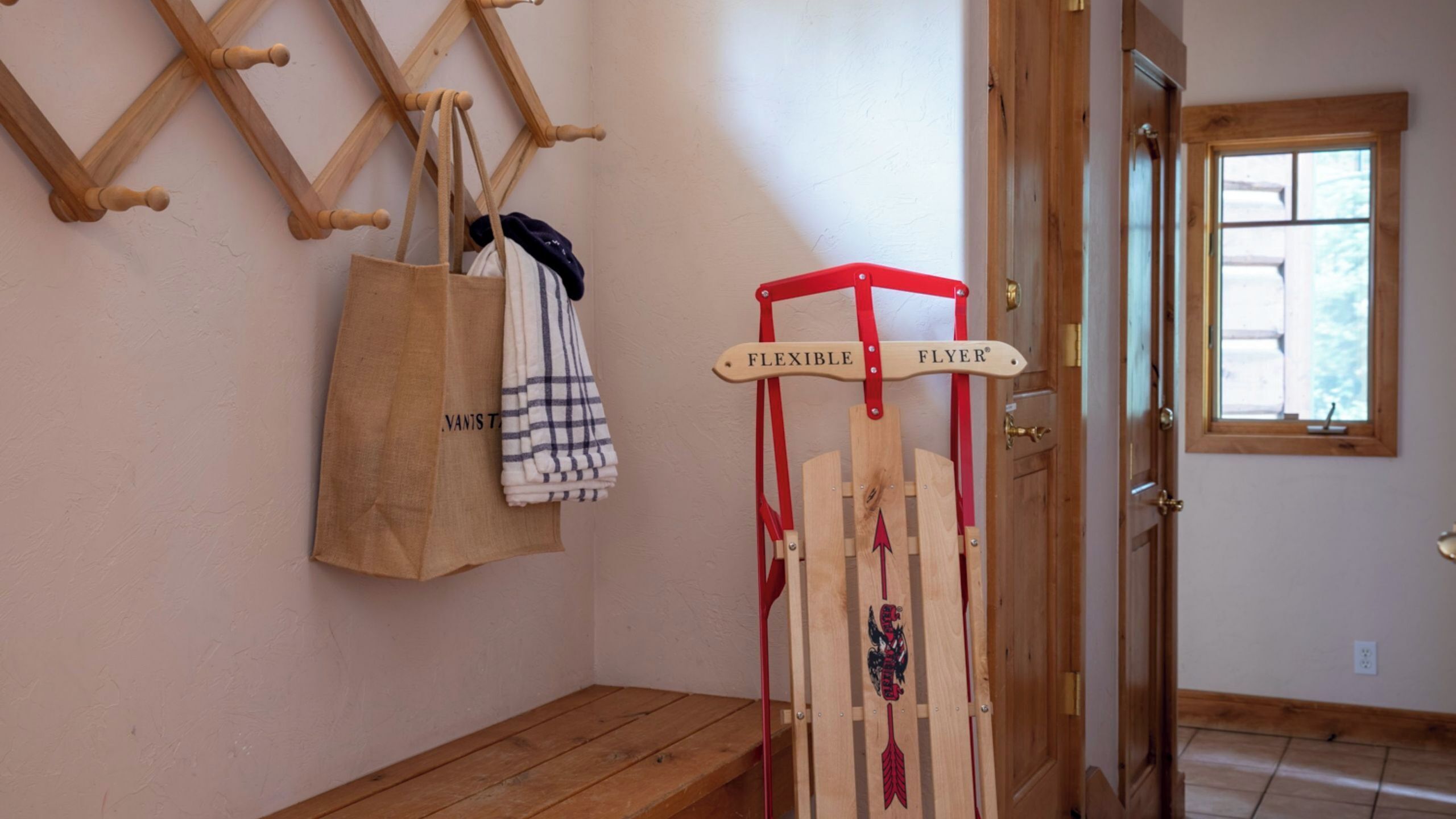 A wooden bench, a wooden rack with bags, and a door with a window.