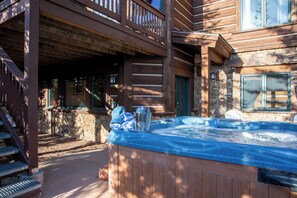 A wooden cabin with a hot tub, stone walls, and a balcony.