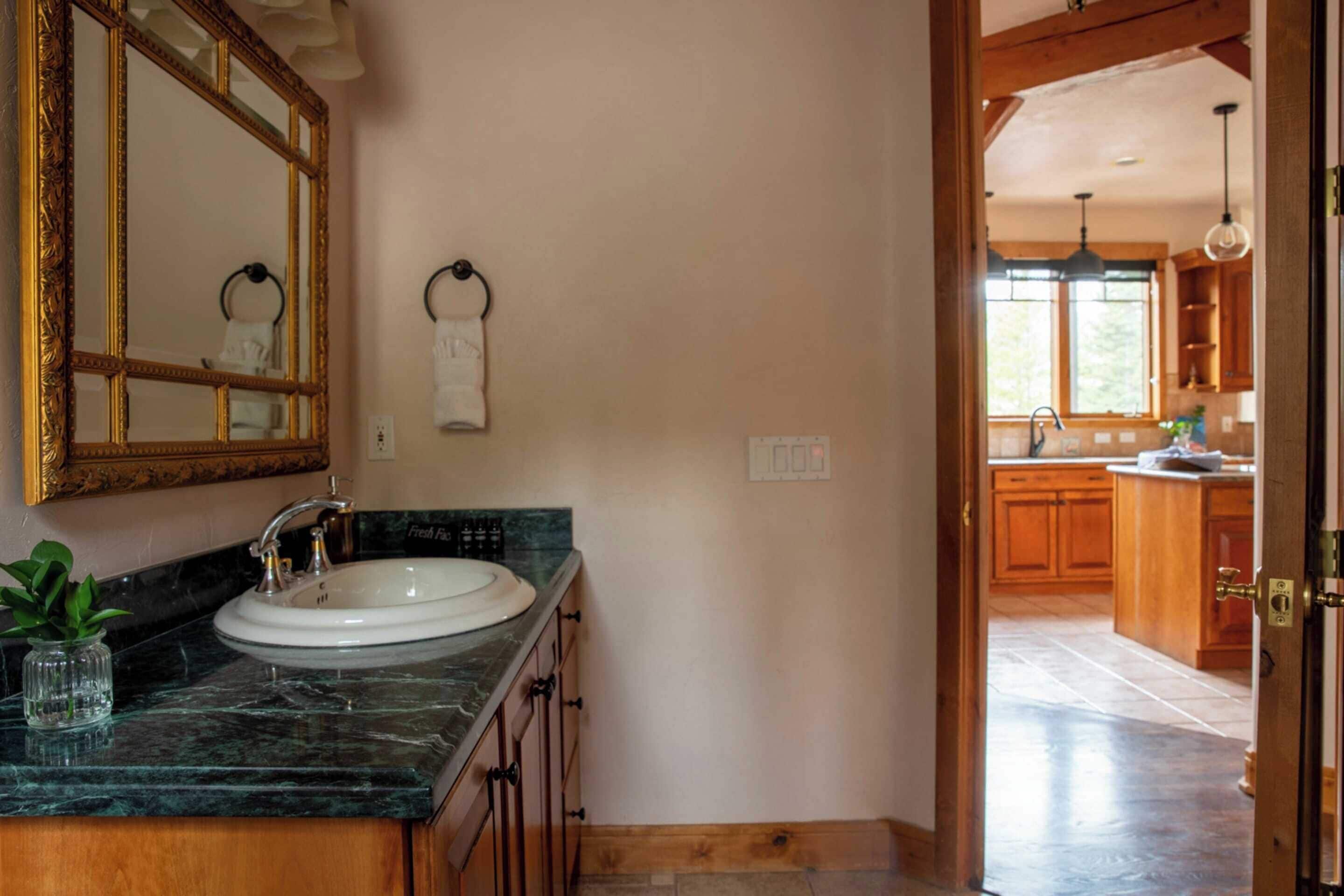 Une salle de bain avec un lavabo en marbre, un grand miroir et un porte-serviettes.