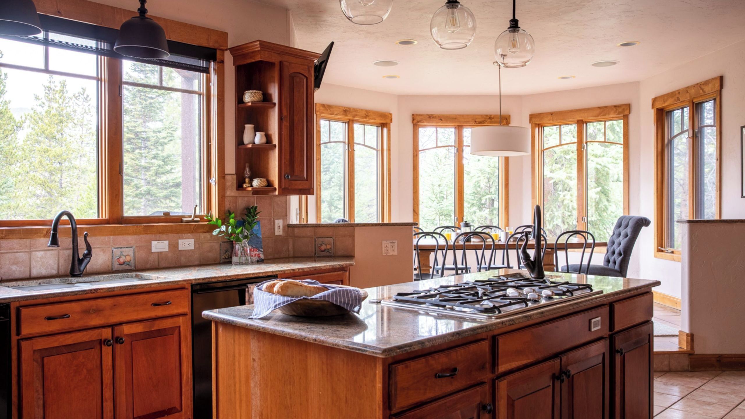 A kitchen with wooden cabinets, a central island, a stove, and large windows.
