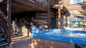 A wooden cabin with a hot tub, stone walls, and a balcony.