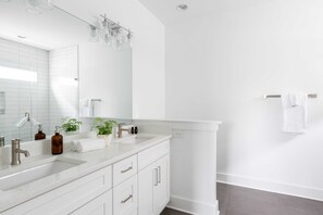 A modern bathroom with two sinks, a large mirror, and a towel rack.