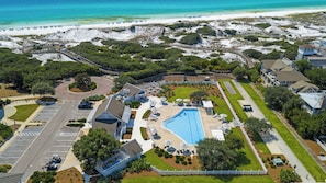 Vue aérienne d’un complexe hôtelier doté d’une piscine, d’un accès à la plage et d’un parking.