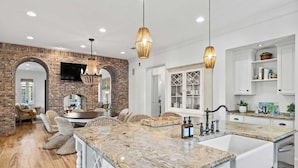 A spacious kitchen with a large island, white cabinetry, and a brick accent wall.