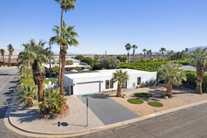 A modern building with a garage, surrounded by palm trees and landscaped areas. - The Llama House by Avantstay Featured on Hgtv, Resort Style, Pool & Spa! Permit#4277 (Palm Springs)