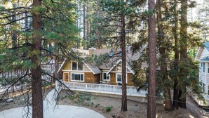A cabin with a wooden exterior, a fenced deck, and a stone chimney. - Hartwood by Avantstay Cozy Big Bear Abode w/ Spacious Deck & Stone Fireplace (Big Bear Lake)