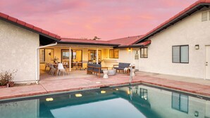 Ein Pool mit einer Terrasse, einem Esstisch und Sitzgelegenheiten im Freien.