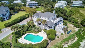 A large house with a swimming pool surrounded by lush greenery and a well-maintained lawn.