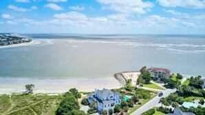 A coastal property with a large house, a swimming pool, and a beach view.