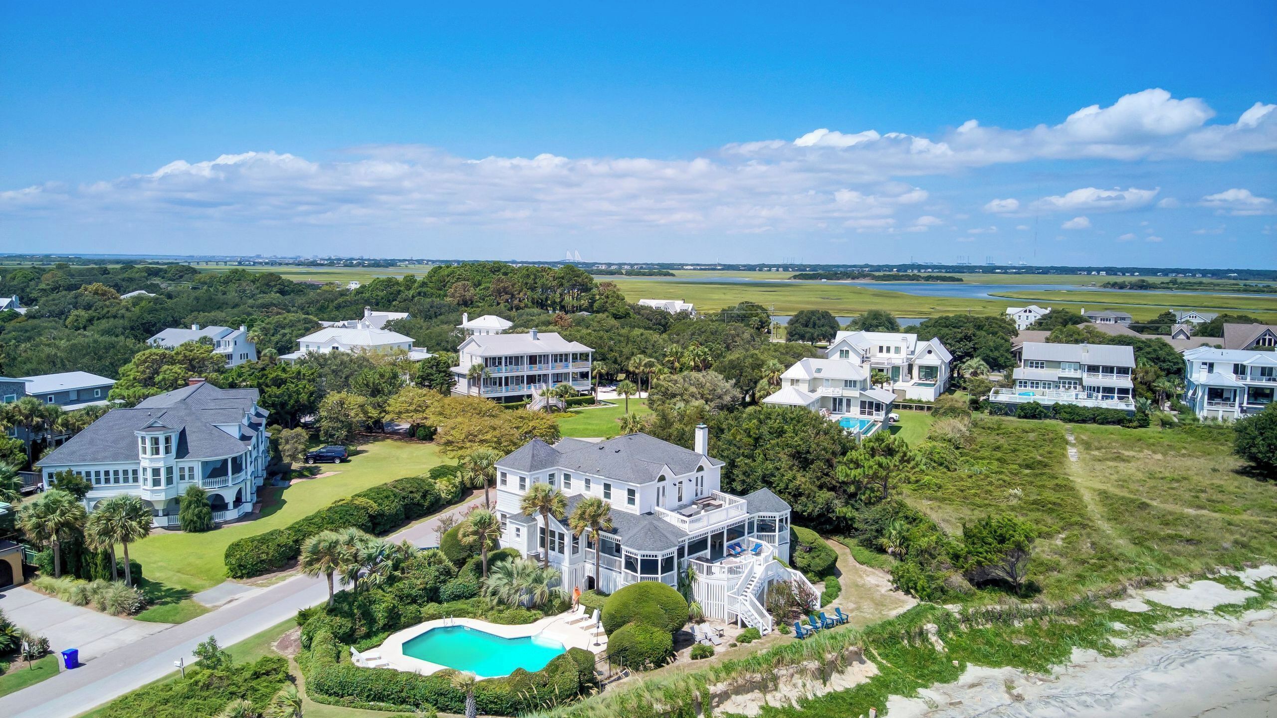 A coastal residential area with multiple houses, a swimming pool, and a golf course in the background.