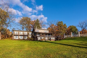 A two-story house with a large front yard and a wooden deck. - Shakespeare on the Hudson by Avantstay Two Home Buyout on the Hudson River! 22 Bedrooms! (Catskill)