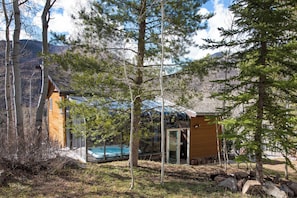A cabin with a glass-enclosed pool, surrounded by trees and mountains. - Condor by Avantstay Gorgeous Mountain Home w/ Hot Tub & Sauna (Vail)