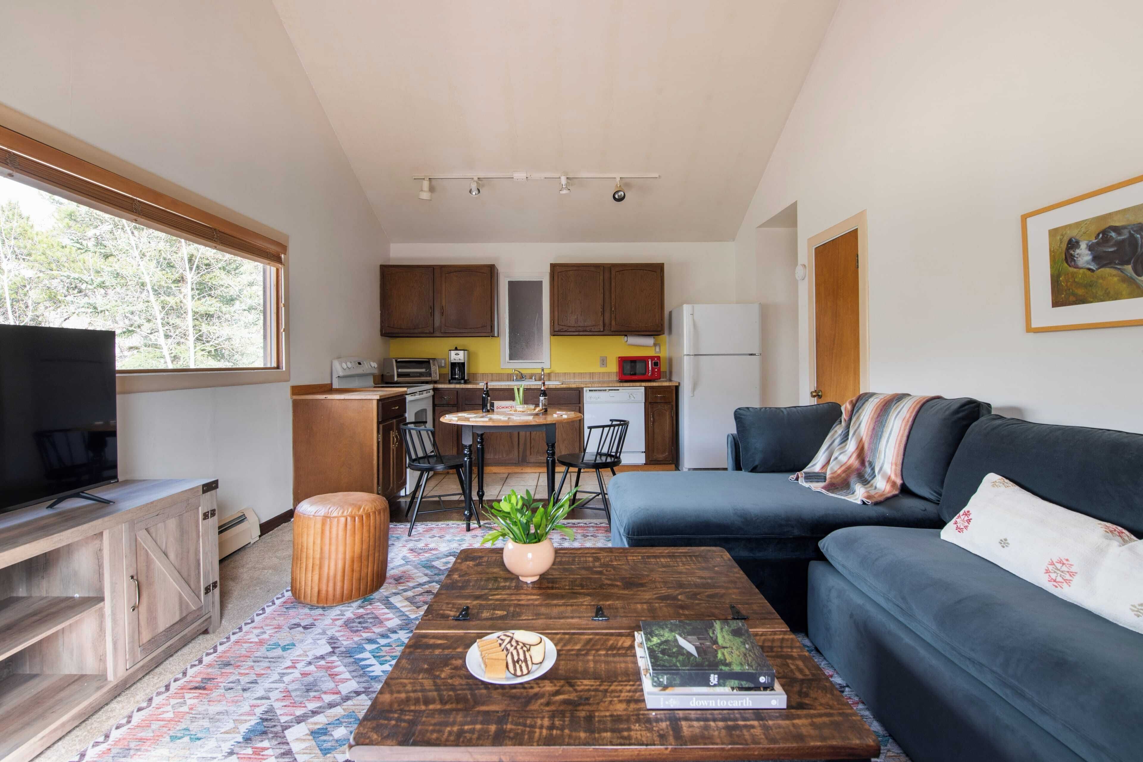A compact living space with a kitchenette, a sofa, a coffee table, and a television.