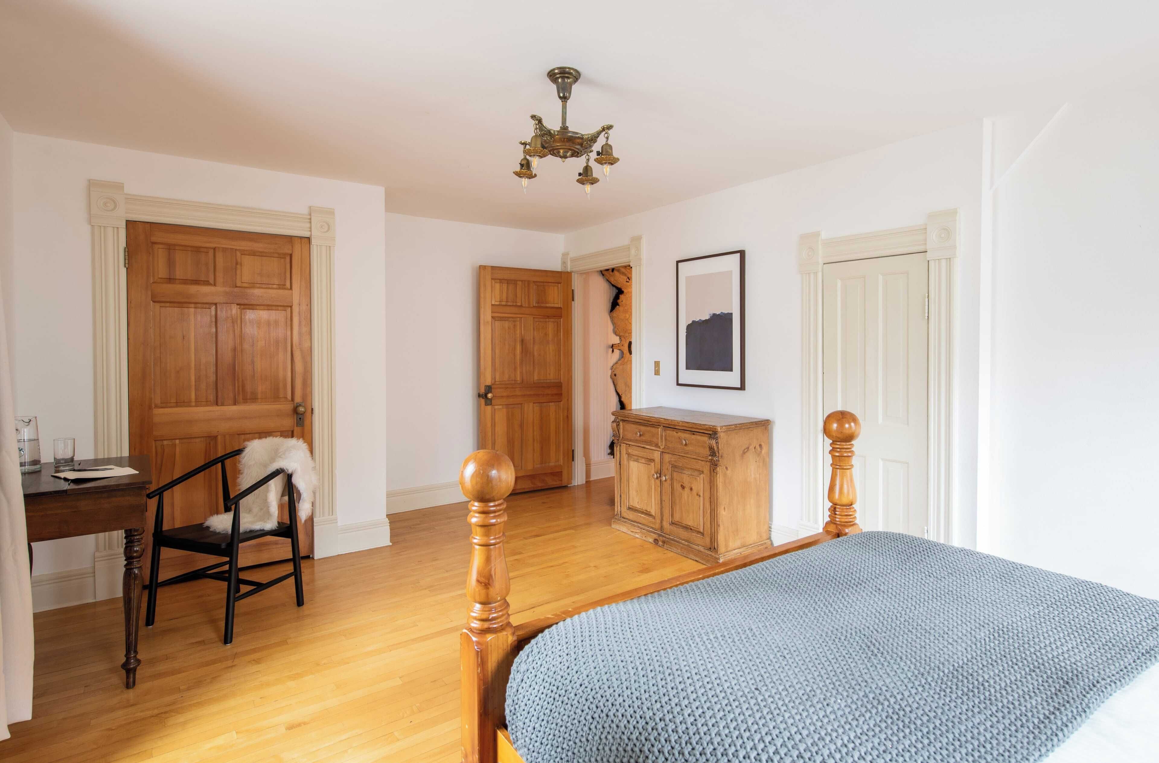 Ein Schlafzimmer mit einem hölzernen Bett, einem Schreibtisch, einem Stuhl und einem Kleiderschrank.
