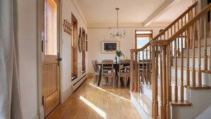 A hallway with wooden flooring, a dining area with a table and chairs, and a staircase with wooden railings. - Condor by Avantstay Gorgeous Mountain Home w/ Hot Tub & Sauna (Vail)