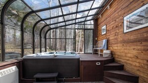 A hot tub area with a glass enclosure, wooden deck, and steps leading to a seating area. - Condor by Avantstay Gorgeous Mountain Home w/ Hot Tub & Sauna (Vail)