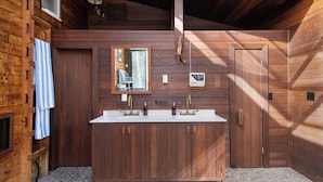 A wooden cabin bathroom with a double sink, wooden cabinets, a mirror, and a towel hanging on the wall. - Condor by Avantstay Gorgeous Mountain Home w/ Hot Tub & Sauna (Vail)