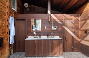 A wooden cabin bathroom with a double sink, wooden cabinets, a mirror, and a towel hanging on the wall. - Condor by Avantstay Gorgeous Mountain Home w/ Hot Tub & Sauna (Vail)