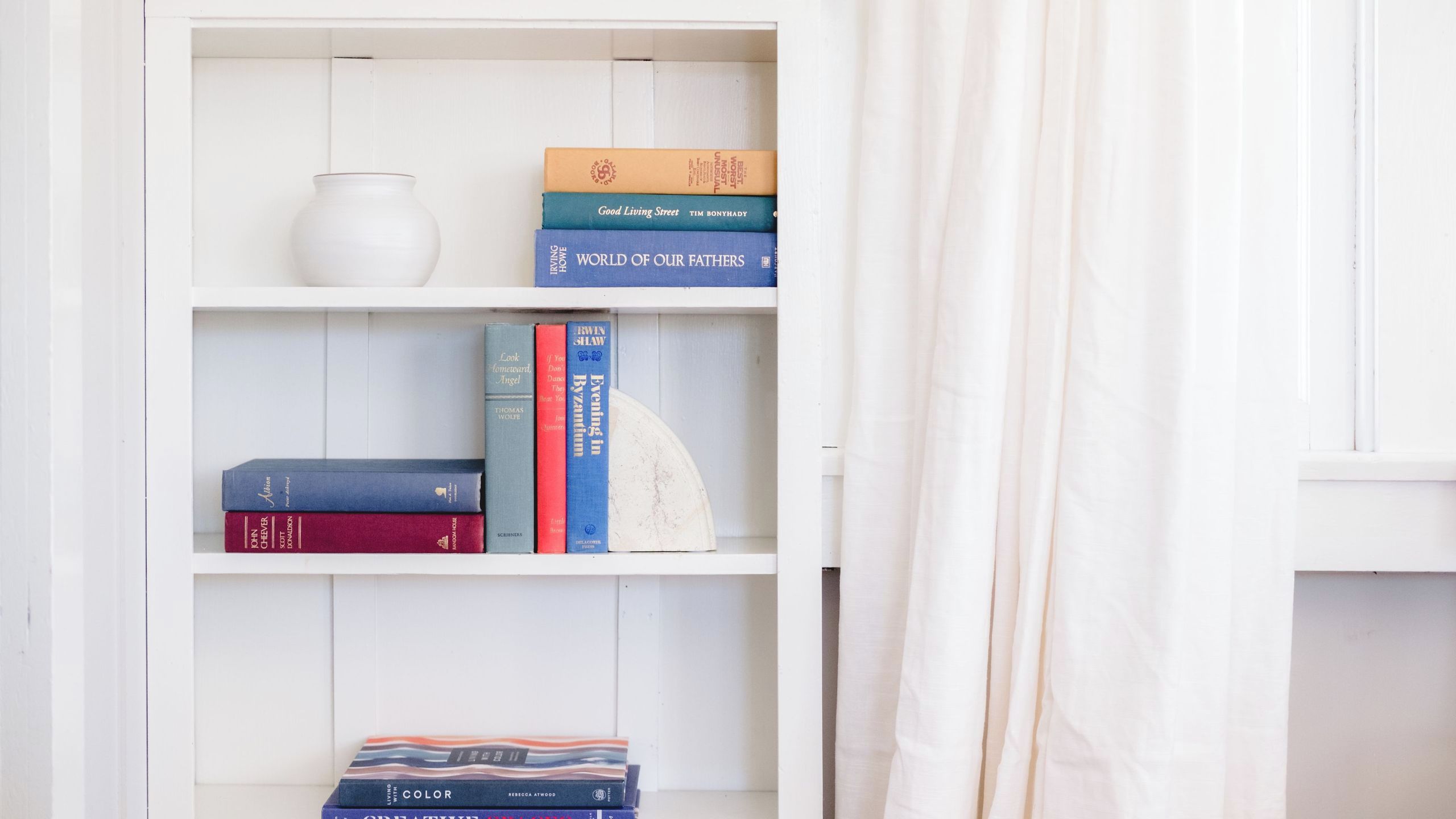 Ein Bücherregal mit Büchern und einer weißen Vase.