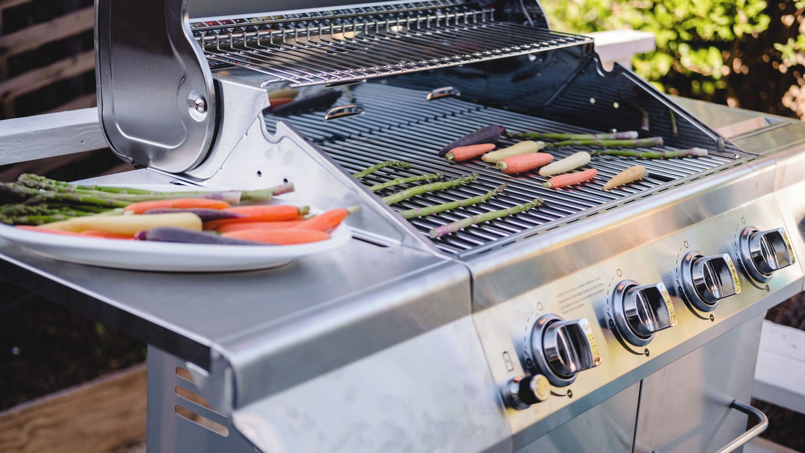 Una parrilla de acero inoxidable con varios quemadores y un plato de verduras.