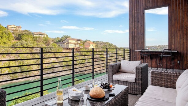 Ein Balkon mit Korbmöbeln, einer Weinflasche und einem Brot.