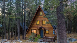 A cabin with a triangular roof, multiple windows, and a front door.