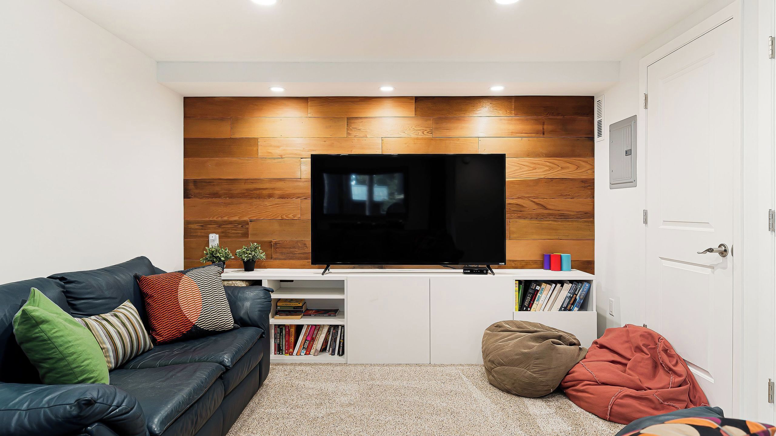 A living room with a TV, a sofa, a bookshelf, and a door.