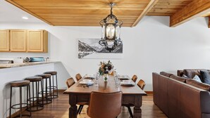 A dining area with a wooden table, chairs, a sofa, and a chandelier. - Riverside Condos C102 by Avantstay Condo Close To Downtown, Town Park & Ski Lift #8 (Telluride)