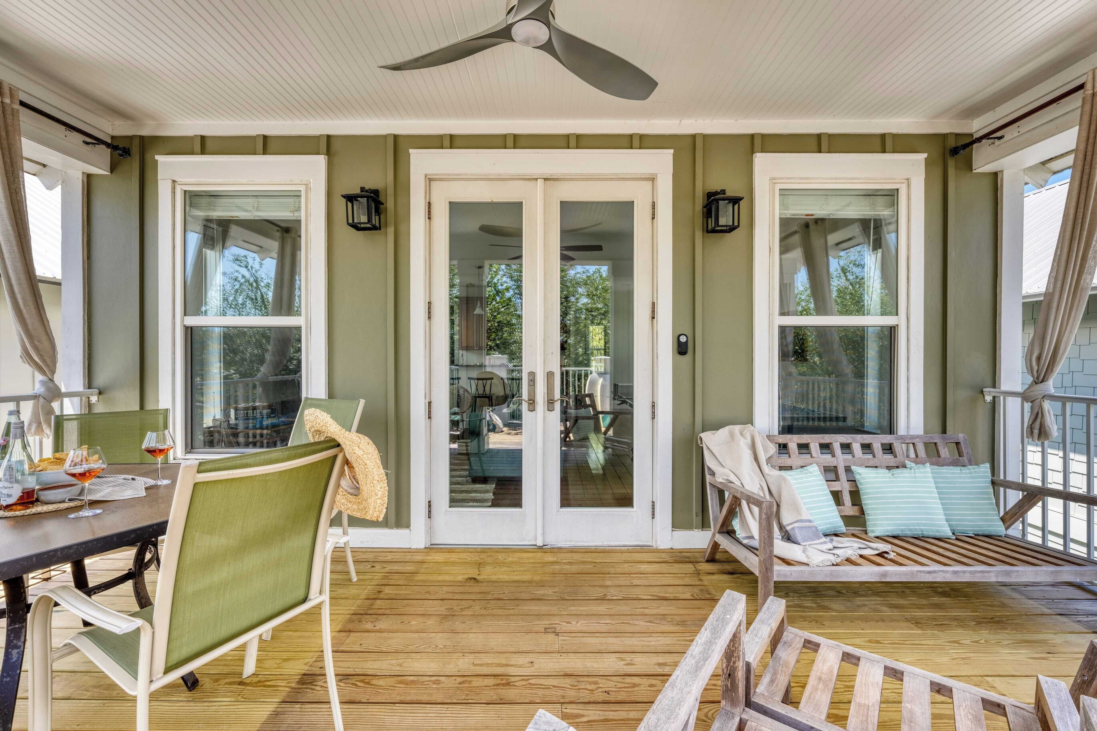 A covered porch with a dining table, chairs, and a wooden bench.