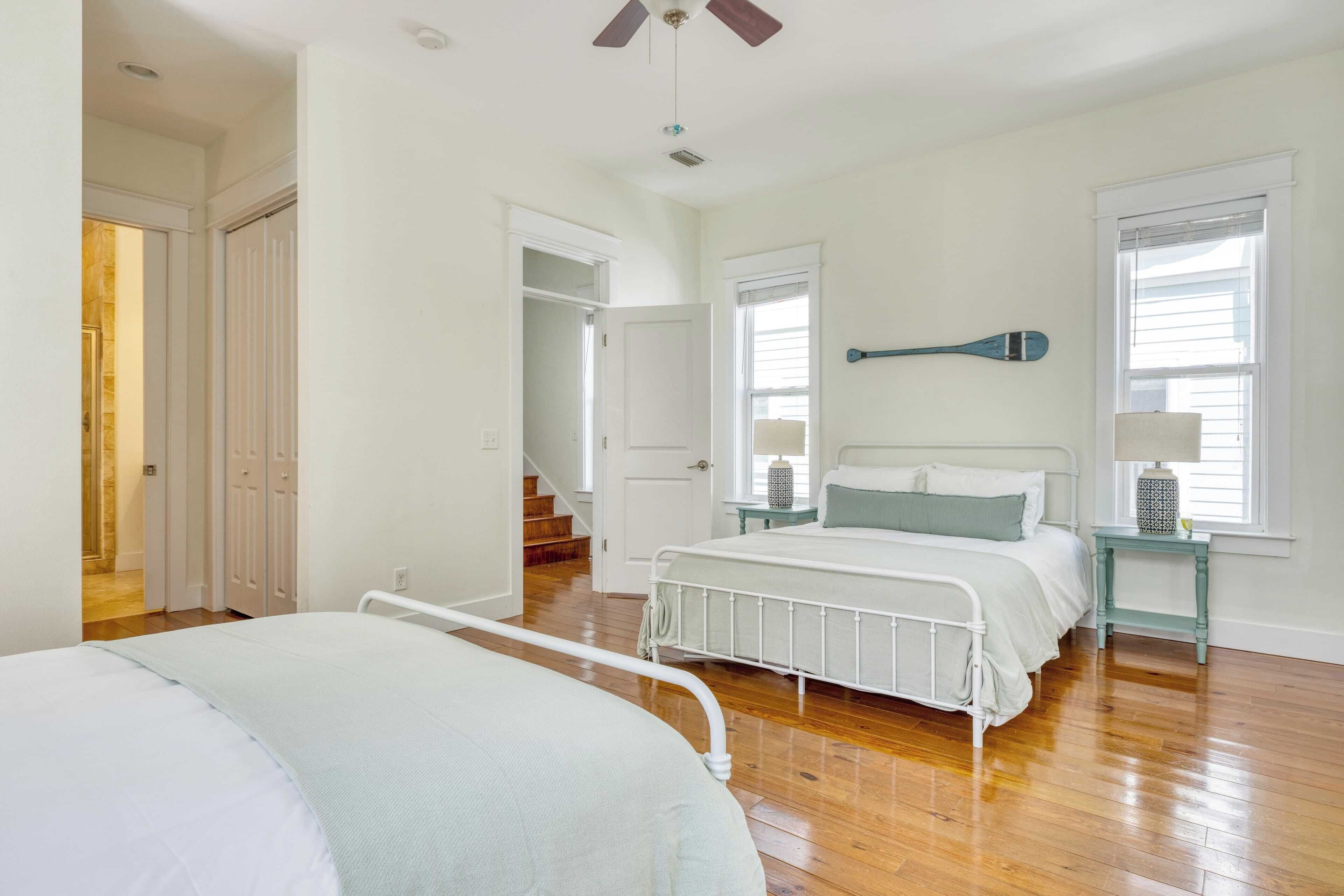 A bedroom with a bed, a nightstand, a window, and a door leading to another room.