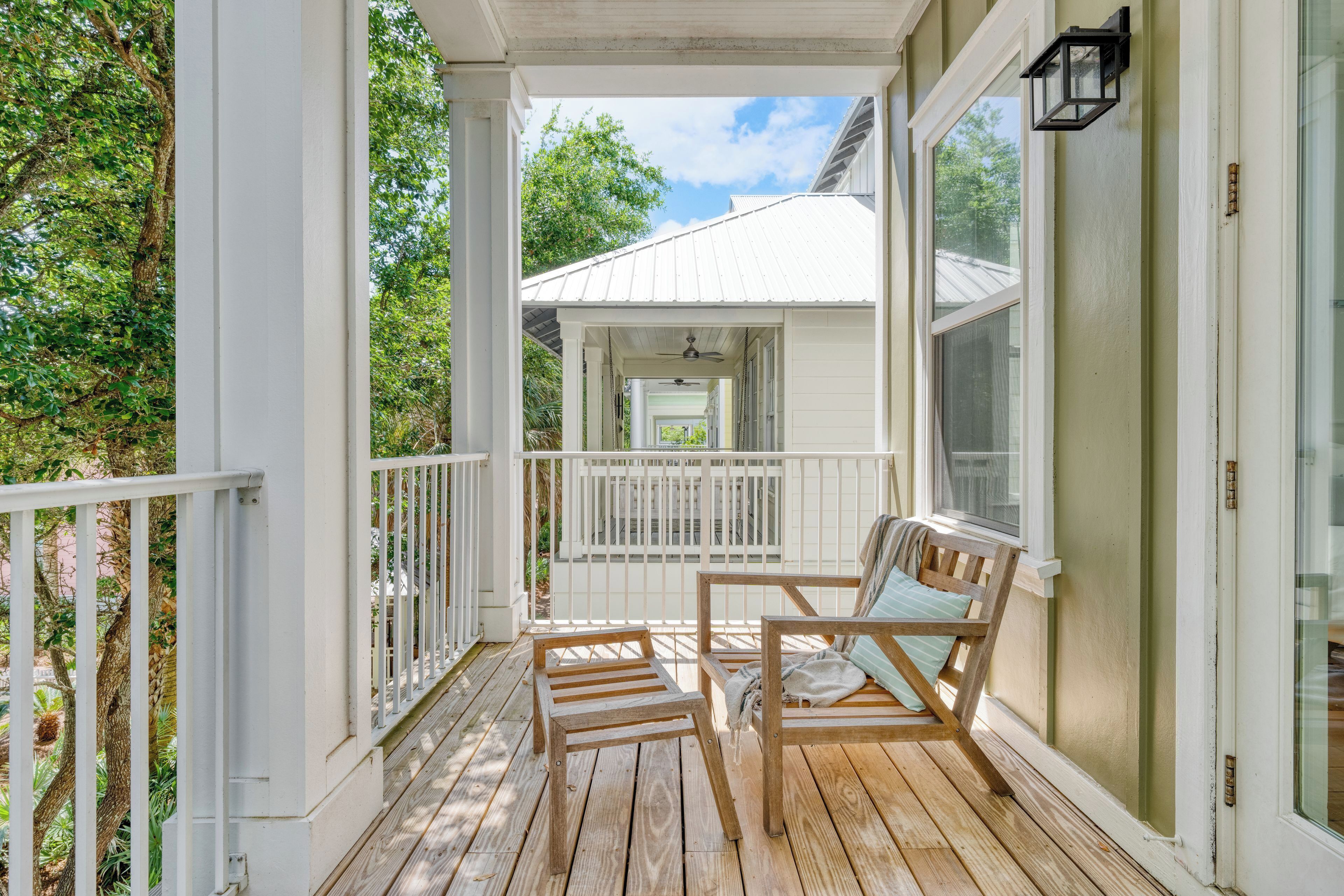 Une véranda en bois avec une balustrade blanche, un banc et une chaise.