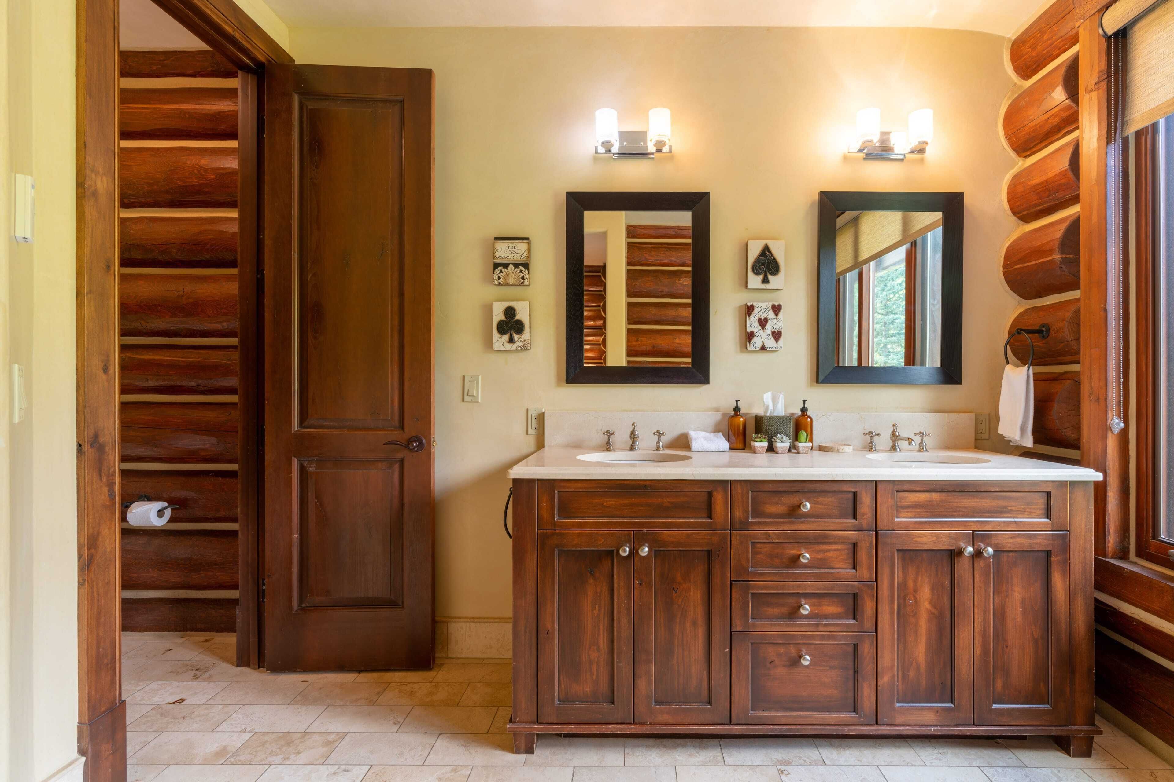 Une salle de bain en bois avec un grand meuble-lavabo, deux appliques murales et un miroir.