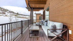 En träveranda med en soffa och ett bord, med utsikt över ett snötäckt landskap.