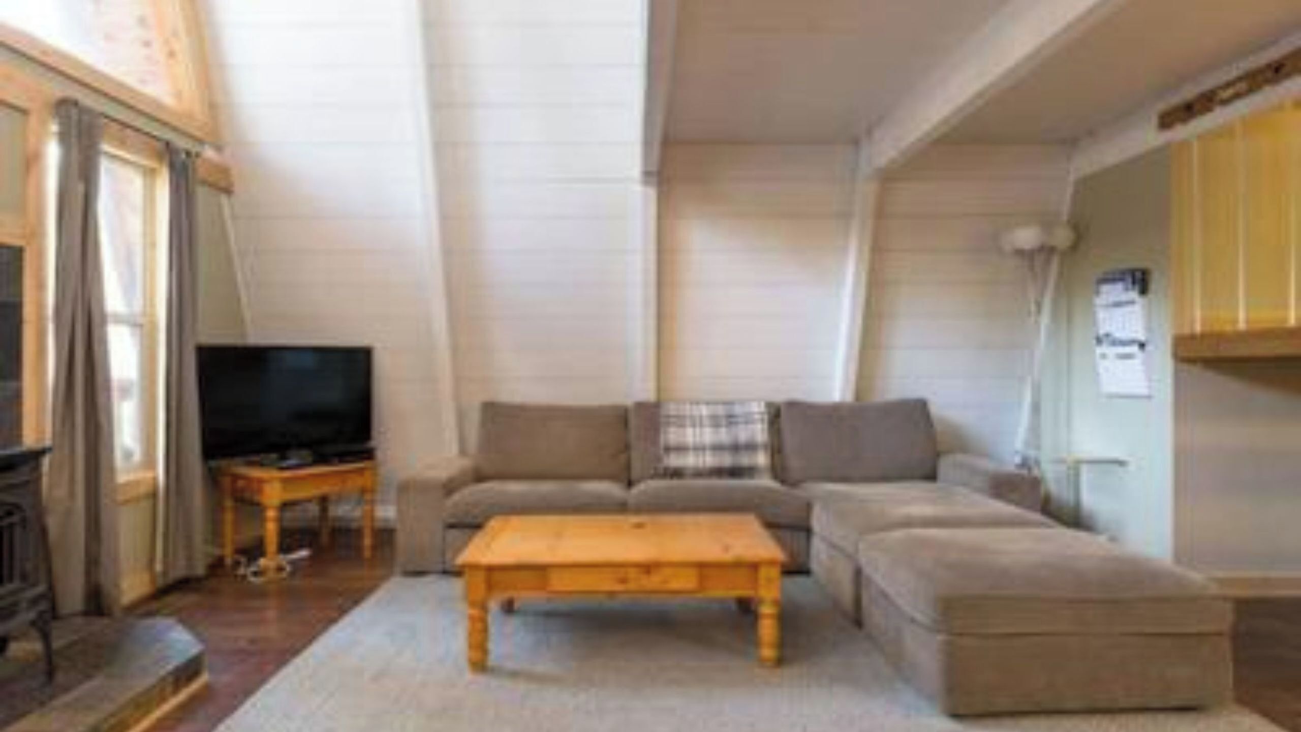 A living room with a sofa, a coffee table, a television, and a fireplace.