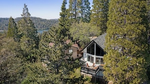 A house surrounded by dense forest with a lake in the background.