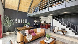 A modern living space with a loft area, a dining area, and a kitchen.