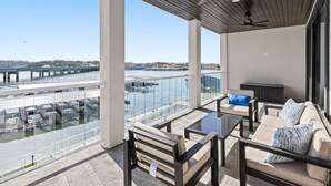 Un balcone con vista su un ponte e sull'acqua, arredato con un divano, sedie e un tavolo.