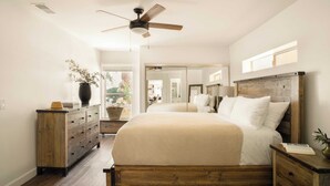A bedroom with a wooden bed, a dresser, a nightstand, a ceiling fan, and a large mirror. - Private Temecula Wine Country Estate With Pool, Hot Tub, Mini Golf & Stunning Patio (Temecula)