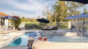 A pool area with lounge chairs, a hot tub, and umbrellas. - Private Temecula Wine Country Estate With Pool, Hot Tub, Mini Golf & Stunning Patio (Temecula)