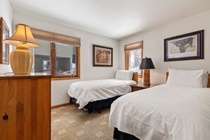 A hotel room with two single beds, a wooden desk, a lamp, and framed artwork on the walls. - Riverside Condos A103 by Avantstay Condo Close To Downtown, Town Park & Ski Lift #8 (Telluride)