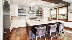 A modern kitchen with a large island, bar stools, and a stainless steel refrigerator. - Modern 5bdr Right off Main Street w/ Hot Tub Main Street Escape by Avantstay (Park City)