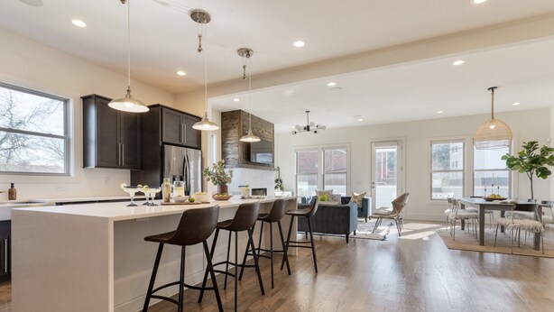 A spacious kitchen with a large island, dark cabinetry, and modern pendant lighting.