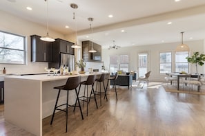 A spacious kitchen with a large island, dark cabinetry, and modern pendant lighting. - Springsteen by Avantstay Stylish Townhouse in Nashville! (Nashville)