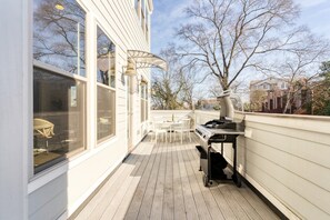 A covered outdoor patio with a grill, white furniture, and large windows. - Springsteen by Avantstay Stylish Townhouse in Nashville! (Nashville)