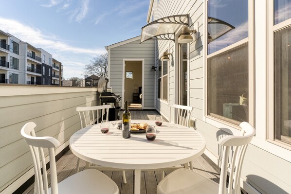 A round white table with chairs on a wooden deck, a bottle, and glasses of red wine. - Springsteen by Avantstay Stylish Townhouse in Nashville! (Nashville)