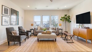 A modern living room with a sofa, armchairs, a coffee table, and a TV.