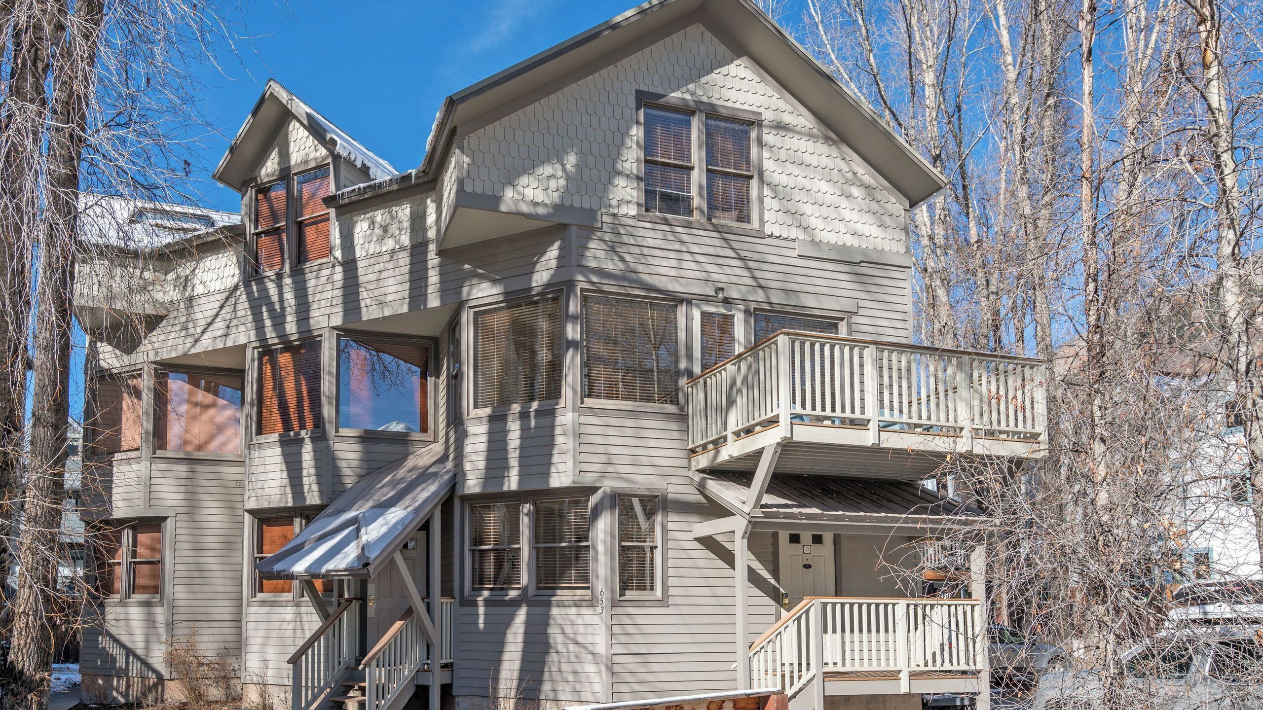 A multi-story house with a balcony, a staircase, and a door with a number.