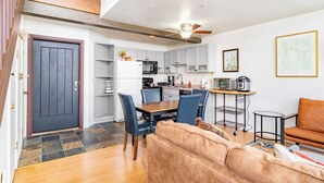 A modern kitchen with grey cabinets, a dining table with blue chairs, and a ceiling fan. - Columbia Place 5 by Avantstay Ski-in/ski-out Unit in Great Location! (Telluride)